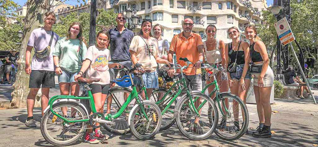 Group of participants, young and old, pose with bikes in front of Casa Milà in Barcelona during Perry Tours Barcelona Bike tour