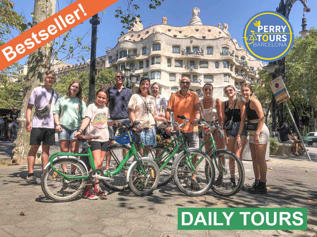 "A diverse group of people posing with bicycles in front of Casa Milà during a Highlights Bike Tour with Perry Tours in Barcelona.
