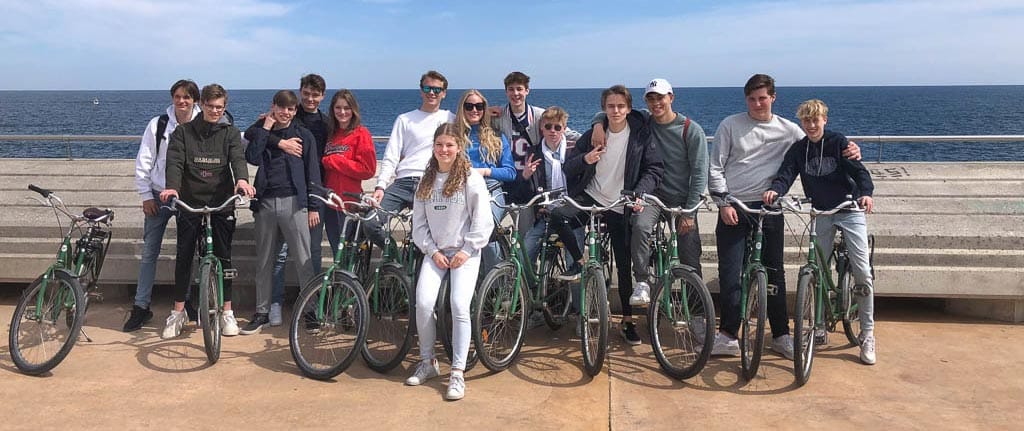 Nederlandse schoolstudenten op fietstour in Barcelona met Perry Tours poseren met de zee op de achtergrond