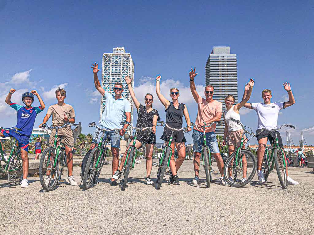 Group of friends posing and having fun during a bike tour at Port Olympic in Barcelona