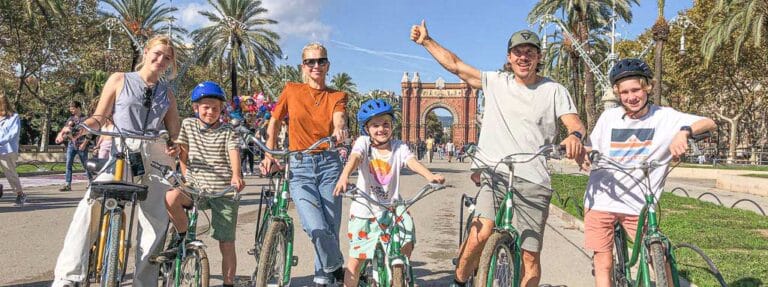 Familie met kinderen op de fiets, plezierig poserend voor de Arc de Triomf in Barcelona